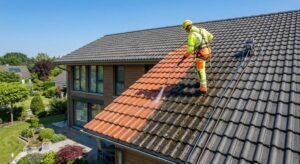 A professional worker cleaning a tiled house roof with a high-pressure cleaner, representing professional roof maintenance services.