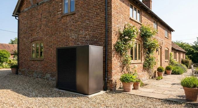 A modern outdoor heat pump unit installed next to a renovated traditional brick house.