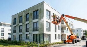 Professional facade cleaning using a hydraulic lift platform instead of scaffolding on a modern residential building.