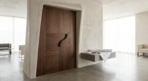 Modern custom-made wooden door in a bright interior with architectural blueprints and a measuring tape.