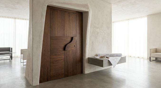Modern custom-made wooden door in a bright interior with architectural blueprints and a measuring tape.