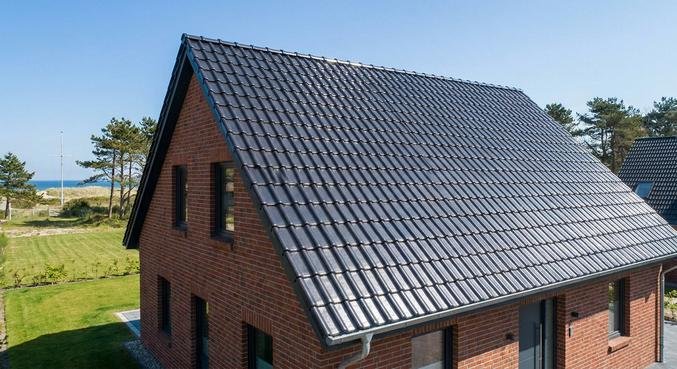 A professionally cleaned and coated roof on a modern brick house in Kiel under a clear blue sky.