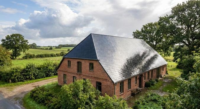 A professional weatherproof roof coating on a traditional house in Schleswig-Holstein under a clearing sky.