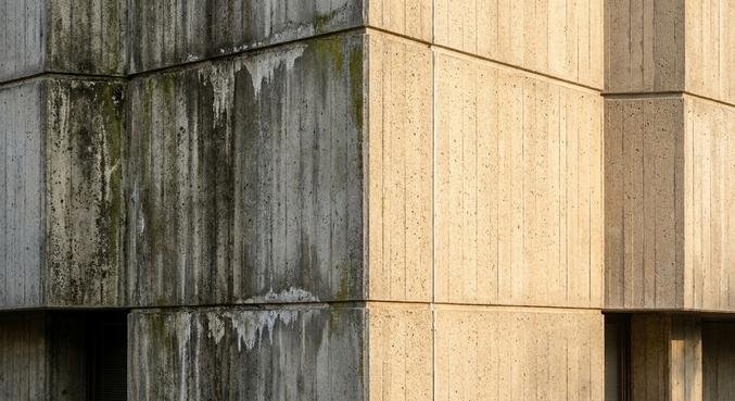 A comparison of a weathered concrete facade and a professionally cleaned, bright concrete surface.